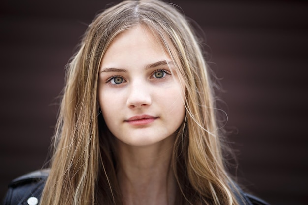 Closeup portrait of little beautiful stylish kid girl with long flowing hair against a brown striped wall