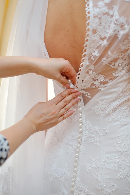 Closeup portrait of a maid of honor helping the bride with her dress