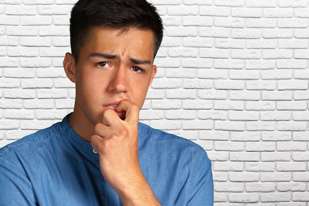 Closeup portrait of a man biting his nails and looking at camera