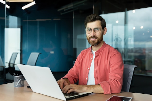 Closeup portrait of mature businessman inside office man with beard and red shirt smiling and