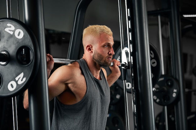 Closeup portrait of a muscular man workout with barbell at gym Brutal bodybuilder athletic man with six pack perfect abs shoulders biceps triceps and chest