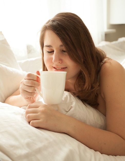 Closeup portrait of pretty woman drinking coffee in bed