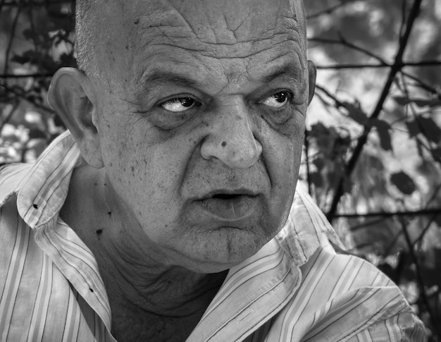 Closeup portrait of a serious old greek retired male with a smile in black and white color