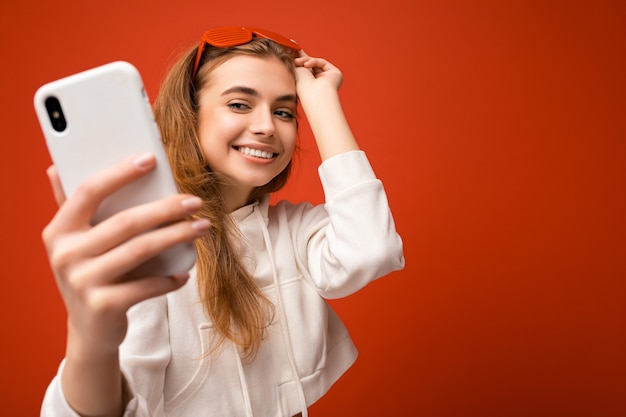 Closeup portrait of sexy attractive positive smiling young blonde woman wearing stylish white hoodie