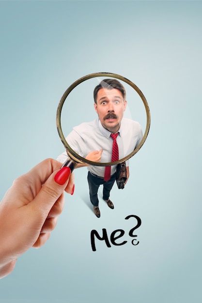 Closeup portrait of smiling, happy, surprised, young business man, funny looking guy asking question, you talking to me, you mean me on blue background. Human emotions, facial expressions