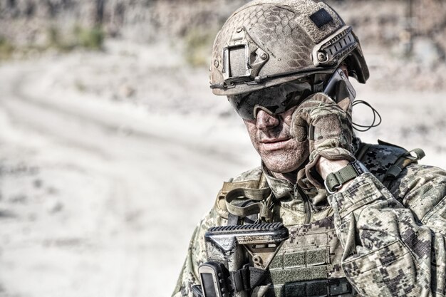 Photo closeup portrait of soldier calliong phone in the desert among rocks