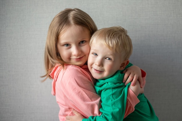 Closeup portrait of two children happy and smiling Blonde brother and sister hugging sibling relationship concept funny kids Boy and girl hugging