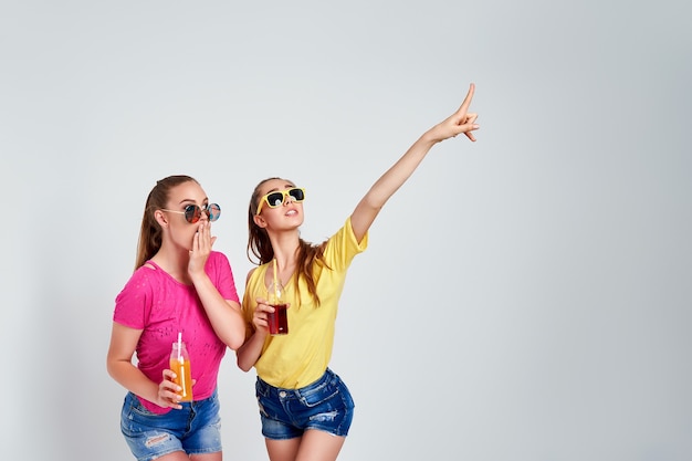 Closeup portrait of two person nice cute fascinating lovely attractive charming cheerful girls in casual clothes with beverage isolated over white background