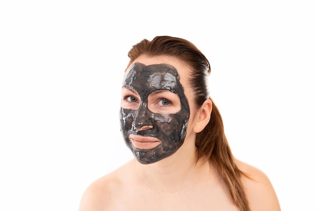 Closeup portrait of a woman after a shower with a black cosmetic clay mask on her face around her