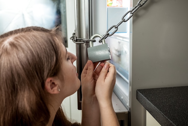 Closeup portrait of woman looking inside locked refrigerator