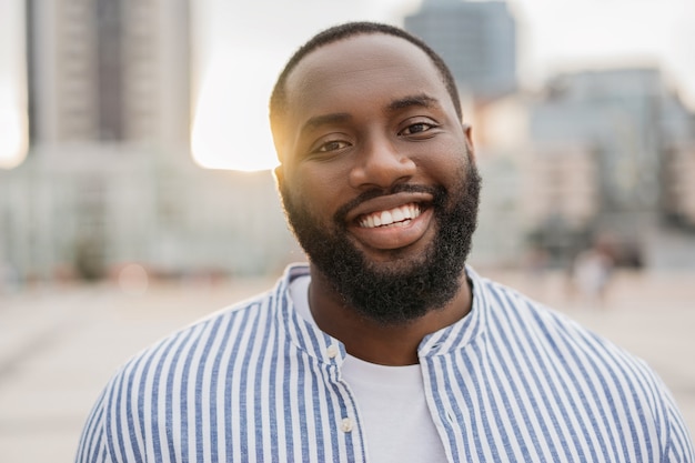 Closeup portrait of young African American, looking at camera, laughing, standing on the street