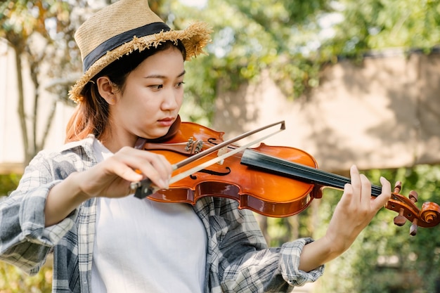 Closeup portrait of Young Asia woman music violinist play violin relax in garden