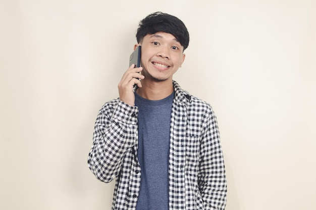 Closeup portrait of young Asian male model wearing plaid shirt talking on phone