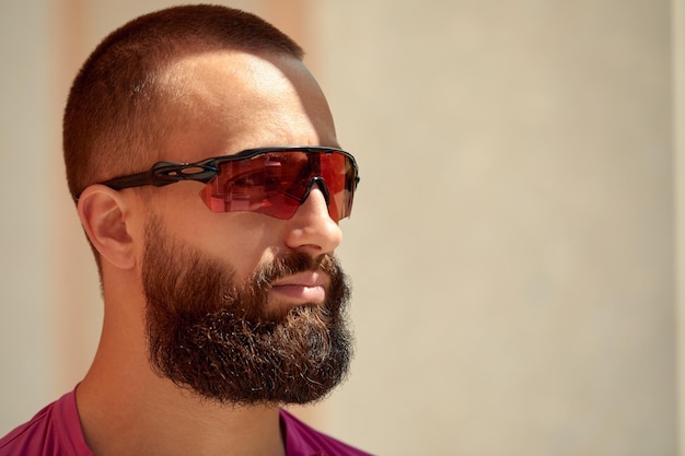 Closeup portrait of young athletic bearded man in sunglasses