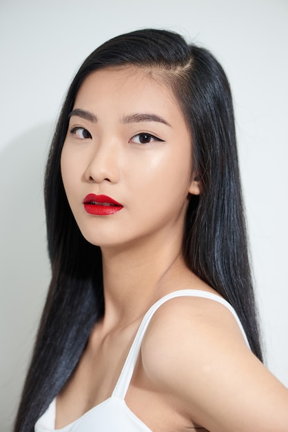 Closeup portrait of a young beautiful attractive asian woman feeling happily over a white background