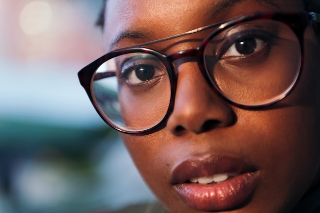 Closeup portrait of a young black woman wearing glasses focus on one eye concept of youth