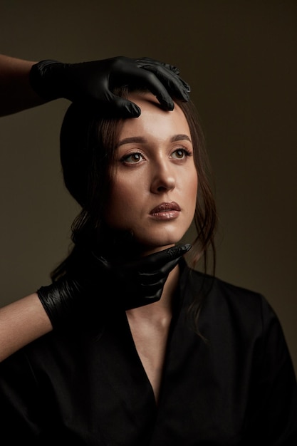 Closeup portrait of young female face is touched by doctors in gloves preparing her for plastic surgery or beautican procedures