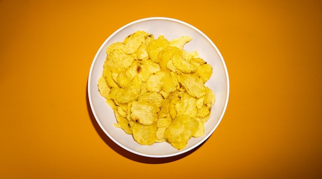 Closeup of potato chips or crisps in bowl against yellow background