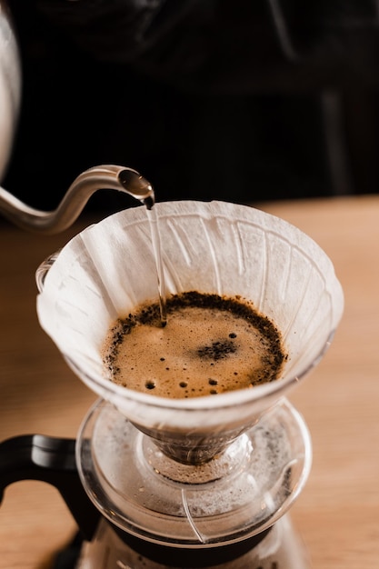 Closeup pour over filter with ground coffee in the funnel in focus Drip filter coffee brewing Pour over alternative method of pouring water over roasted and ground coffee beans contained in filter