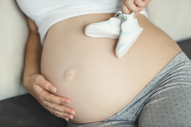 Closeup of pregnant woman holding baby socks on belly