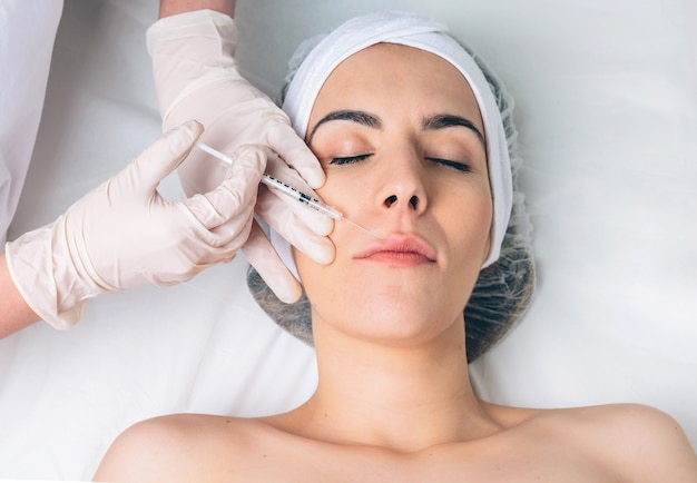 Closeup of pretty woman getting cosmetic injection in the face like a part of the clinic treatment. Medicine, healthcare and beauty concept.