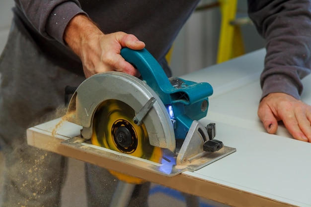 Closeup process of carpenter worker with circular saw machine at wood beam cross cutting wood door c