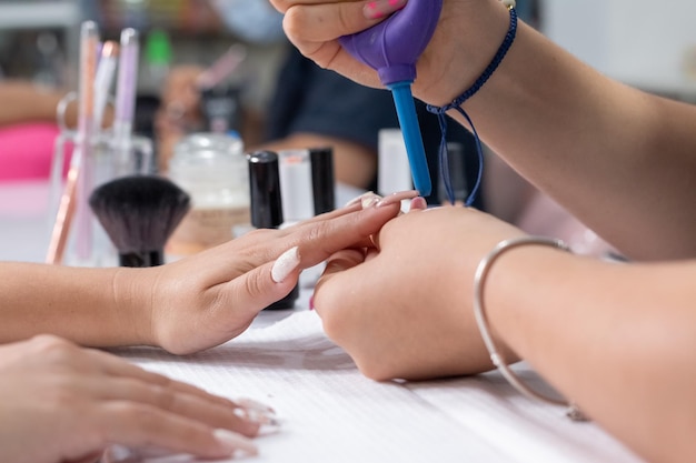 Closeup of a professional manicurist cleaning nails with a handheld air blower