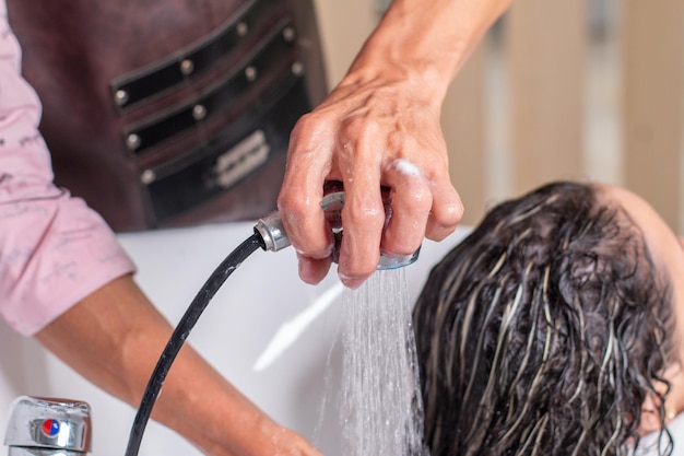 Closeup of a professional stylist rinsing her client's hair in a beauty salon