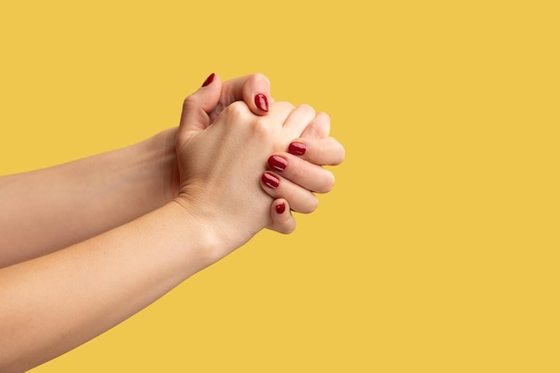 Closeup profile side view of right and left woman palms are connected in lock support and togetherness Indoor studio shot isolated on yellow background