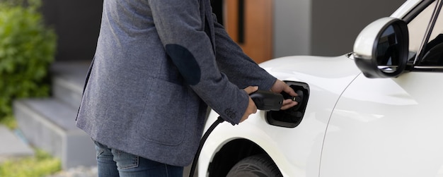 Closeup progressive asian man recharge his EV car at home charging station