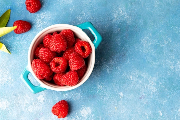 Closeup raspberry fruits in blue bowl blue background top view copy space