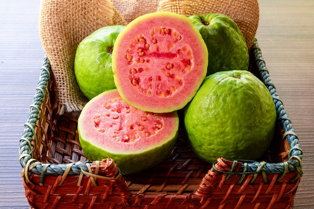 Closeup on red guava sliced with green leaf on rustic wooden table