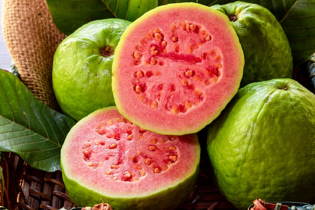 Closeup on red guava sliced with green leaf on rustic wooden table