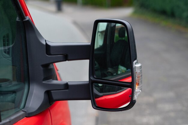 Photo a closeup of a red vehicles side view mirror with a clear view of the cars red paint and a smaller