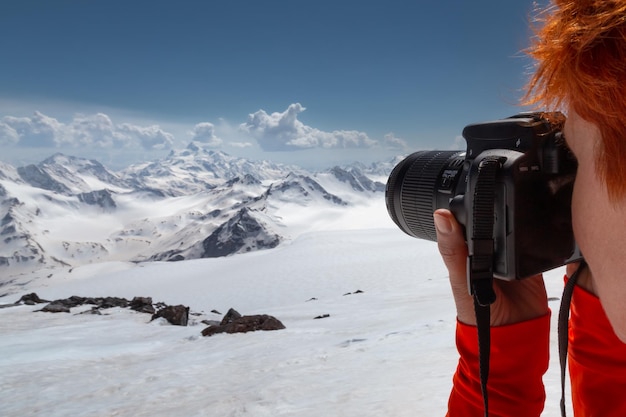 Closeup of redhaired girl photographing mountain landscape with DSLR camera Caucasus Russia