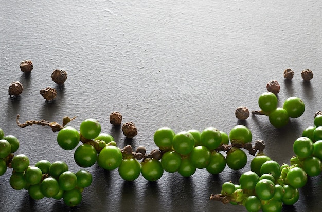 Closeup on resh green peppercorns on gray slate stone, space