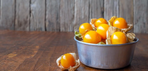 Closeup ripe yellow Cape Gooseberry fruit In a bowl stainless steel on a wooden background