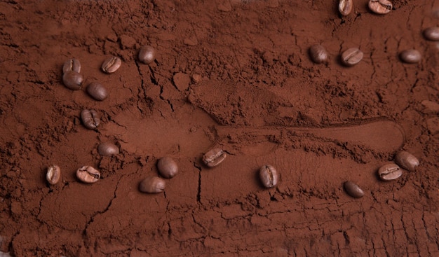 Closeup of roasted ground coffee with coffee beans and the imprint of a coffee spoonproducts