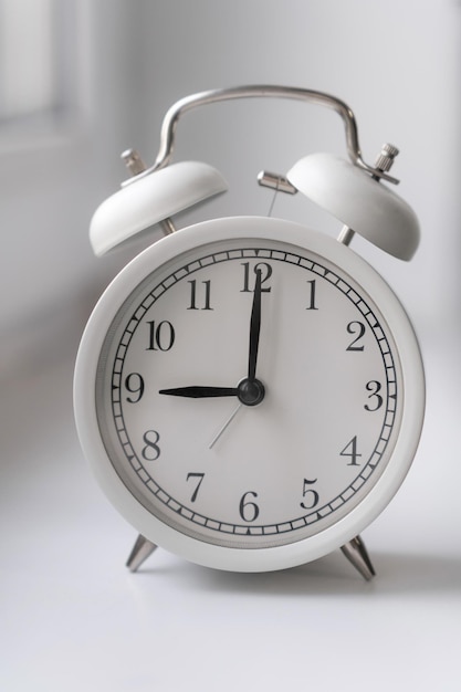 Closeup of a round white alarm clock on a table in the bedroom