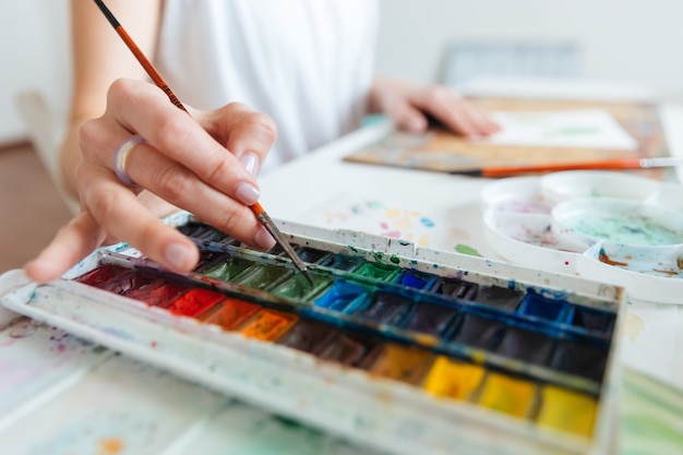 Closeup of set of watercolor paints used by woman artist on the table in workshop