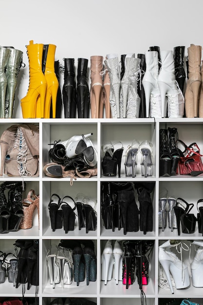 Closeup shelf with many stored pairs of beautiful highheeled shoes for exotic pole dance in studio