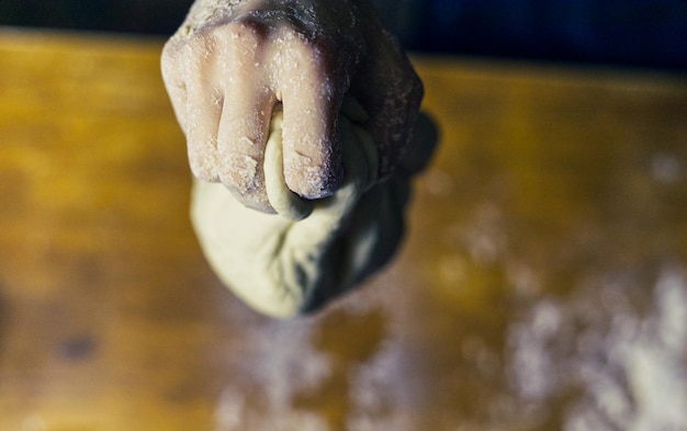 Closeup shot of baker's hands making dough for bread on a wooden table