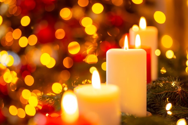 Closeup shot of bright candles in front of fir tree in lights