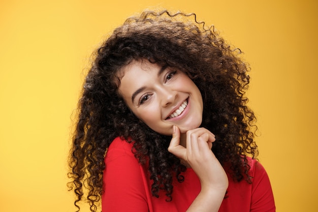 Closeup shot of charming flirty and silly curlyhaired young woman making faces as trying get what wa...