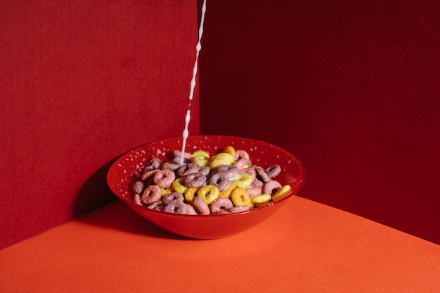 Closeup shot of colourful cereals in a red bowl with milk pouring into it on red corner background