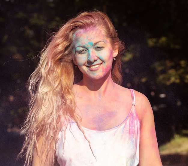 Closeup shot of cool blonde woman covered with colorful dry paint at Holi festival of colors