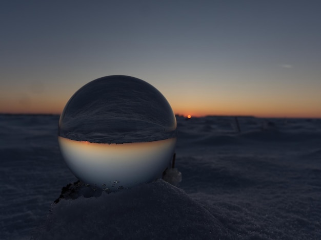 Closeup shot of a crystal ball bottom with winter view at sunset