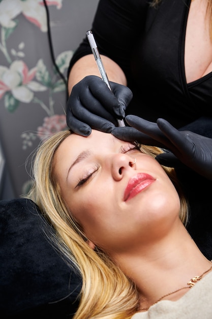 Closeup shot of a female getting her eyebrows fixed by a professional makeup artist