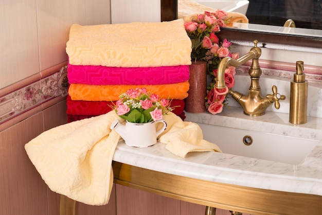 A closeup shot of folded colorful bamboo towels on a bathroom cabinet with a bouquet decoration