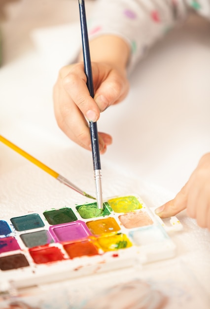 Closeup shot of girl holding brush and painting with watercolor